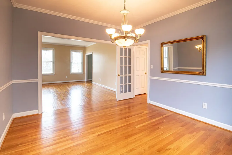 Empty room with hardwood floors, chandelier and french doors